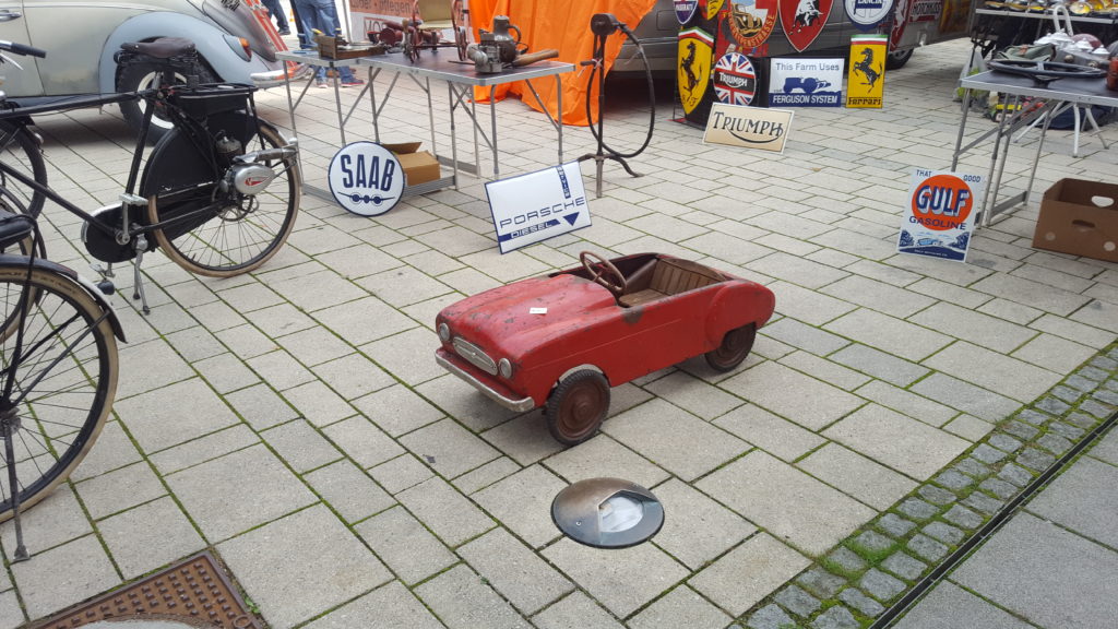 Rotes Oldtimer-Spielzeugauto steht auf dem gepflasterten Austellungsgelaende in Fuerstenfeld