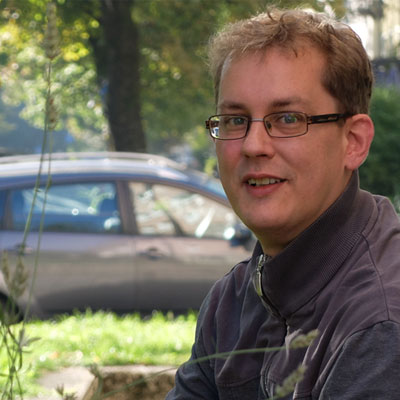 Portraitbild von Werner Kurzlechner mit Auto und Baum im Hintergrund