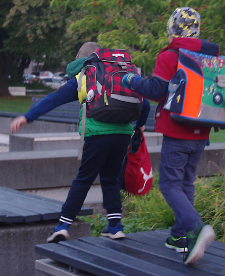 Bus mit Füßen: Zwei Kinder auf dem Schulweg laufen auf einer Parkbank