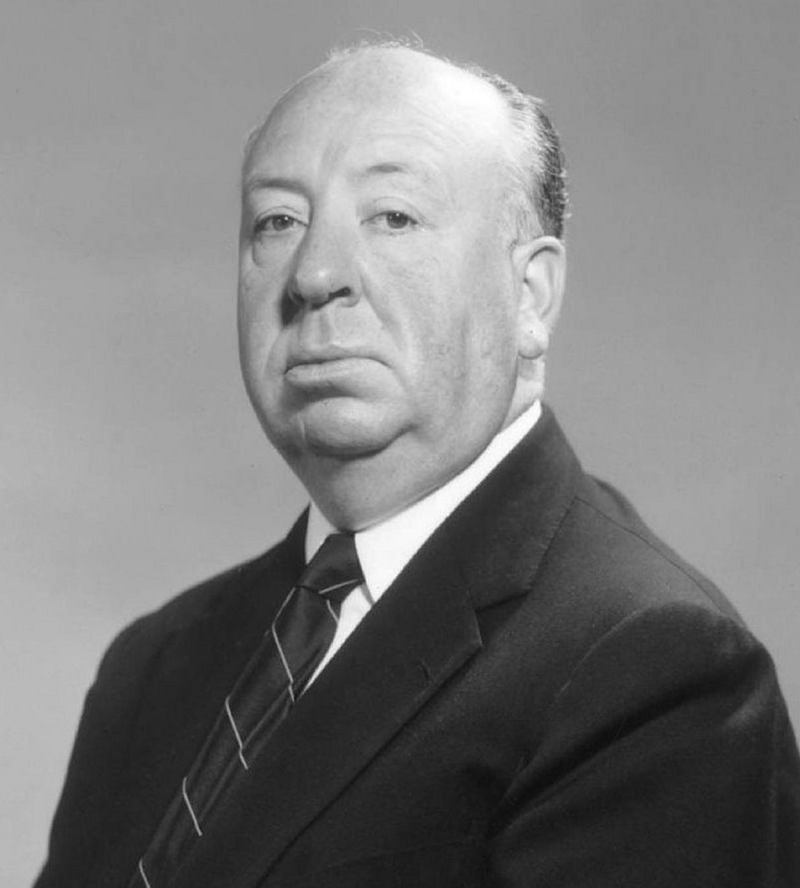 Portraitbild von Alfred Hitchcok, der Anzug und Krawatte trägt