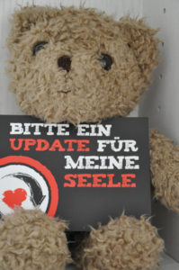 Teddy-Bär hält ein Schild mit der Aufschrift "Bitte um ein Update für meine Seele"