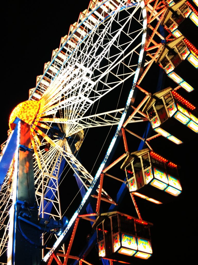Bunt erleuchtetes Riesenrad auf dem Oktoberfest in Nahaufnahme vor schwarzem Nachthimmel