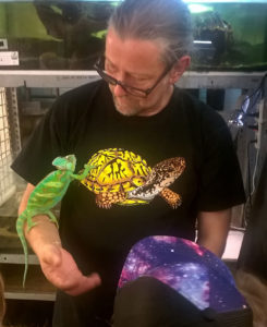 Markus Baur, der Leiter der Reptilienauffangstation München, hat ein grünes Chamäleon auf dem rechten Arm und zeigt es Kindern