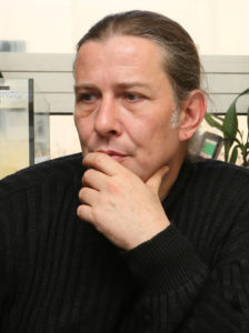 Markus Baur, der Leiter der Reptiliensation München, im schwarzen Pulli, die langen Haare zum Zopf gebunden, 