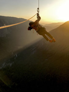 Der Regisseur und Kameramann Jimmy Chin hängt während des Filmdrehs von Free Solo im Seil. Im Hintergrund geht über dem Yosemite Valley die Sonne unter.