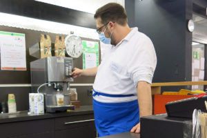 Kaspar Beer, ein Mitarbeiter im Cafe, macht einen Latte Macchiato
