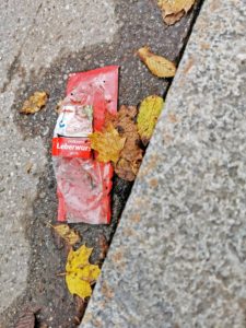 leere Plastikverpackung einer Leberwurst liegt am Straßenrand
