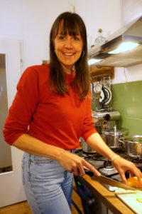 Judith Niemeyer lächelt in die Kamera, trägt einen roen Pullover und schneidet einen Kürbis in ihrer Küche. Foto: Nina Jarosch