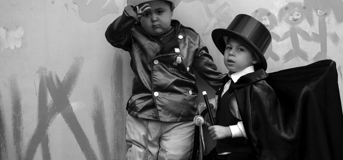 Zwei Kinder, eines mit Handprothese, haben sich mit Hut und Zylinder verkleidet.