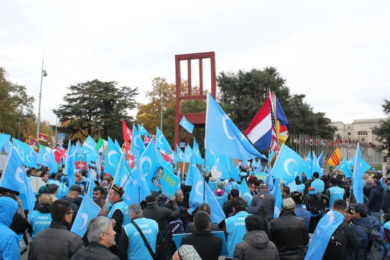 Protestaktion der "Blauen Wölfe" vor dem UN-Gebäude in Genf. Darüber thront das Mahnmal "Broken Chair". Eine Reportage von Friederike Albat