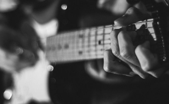 schwarzweiss Foto von Händen die eine e-Gitarre spielen