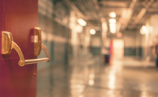 Rote geöffnete Krankenhaustüre mit Blick in eine unscharf fotografierte Station