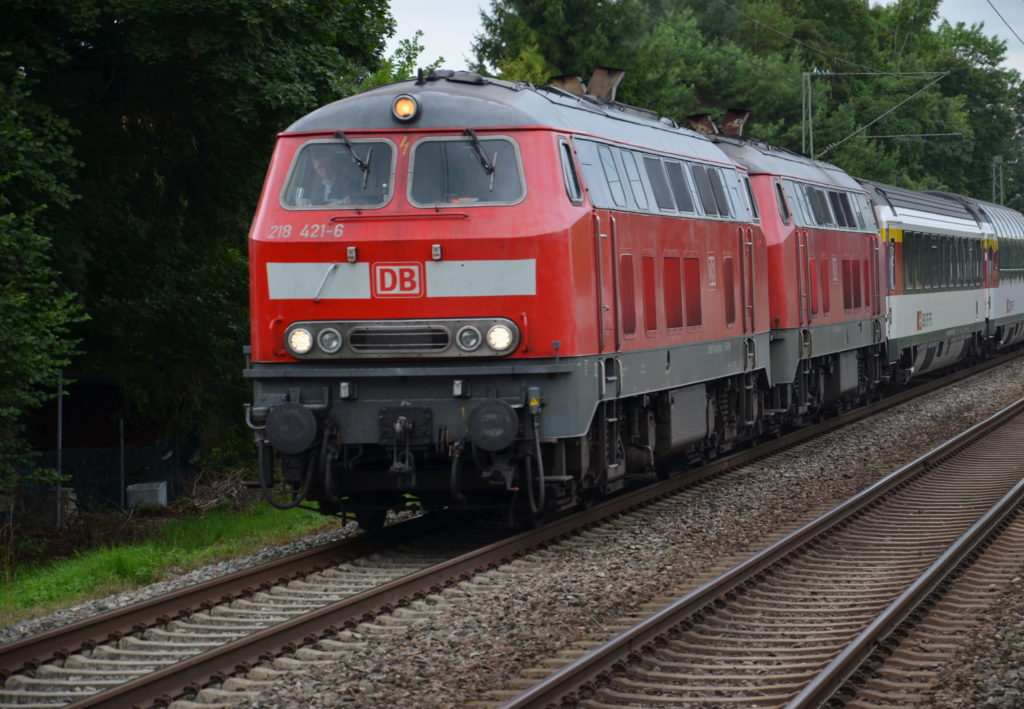 Ein Zug auf Bahnschienen mit einer roten Lok und weiß-grauen Waggons
