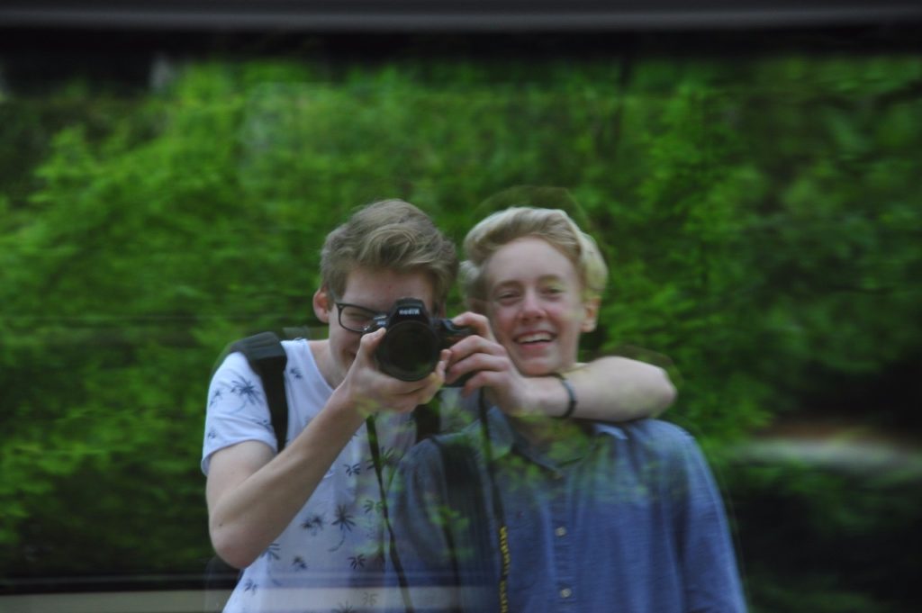 Zwei Freunde fotografieren ihr Spiegelbild im Fenster eines Zuges