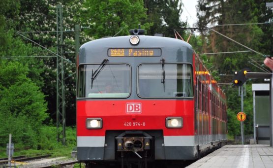 Roter Zug Baureihe 420 steht an einer Bahnhaltestelle im Hintergrund grüne Bäume