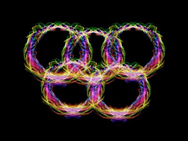 Fünf Olympiaringe aus buntem Neonlicht vor schwarzem Hintergrund