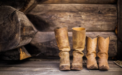 Zwei Paar Cowboystiefel stehen auf Holzboden nebeneinander